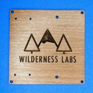 Photo of a laser-cut and engraved wooden board with the Wilderness Labs logo on it.