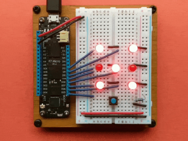 Video of a Meadow board connected to an H shape of red LEDs and a button that cycles the LEDs before showing a number like a roll of a die.