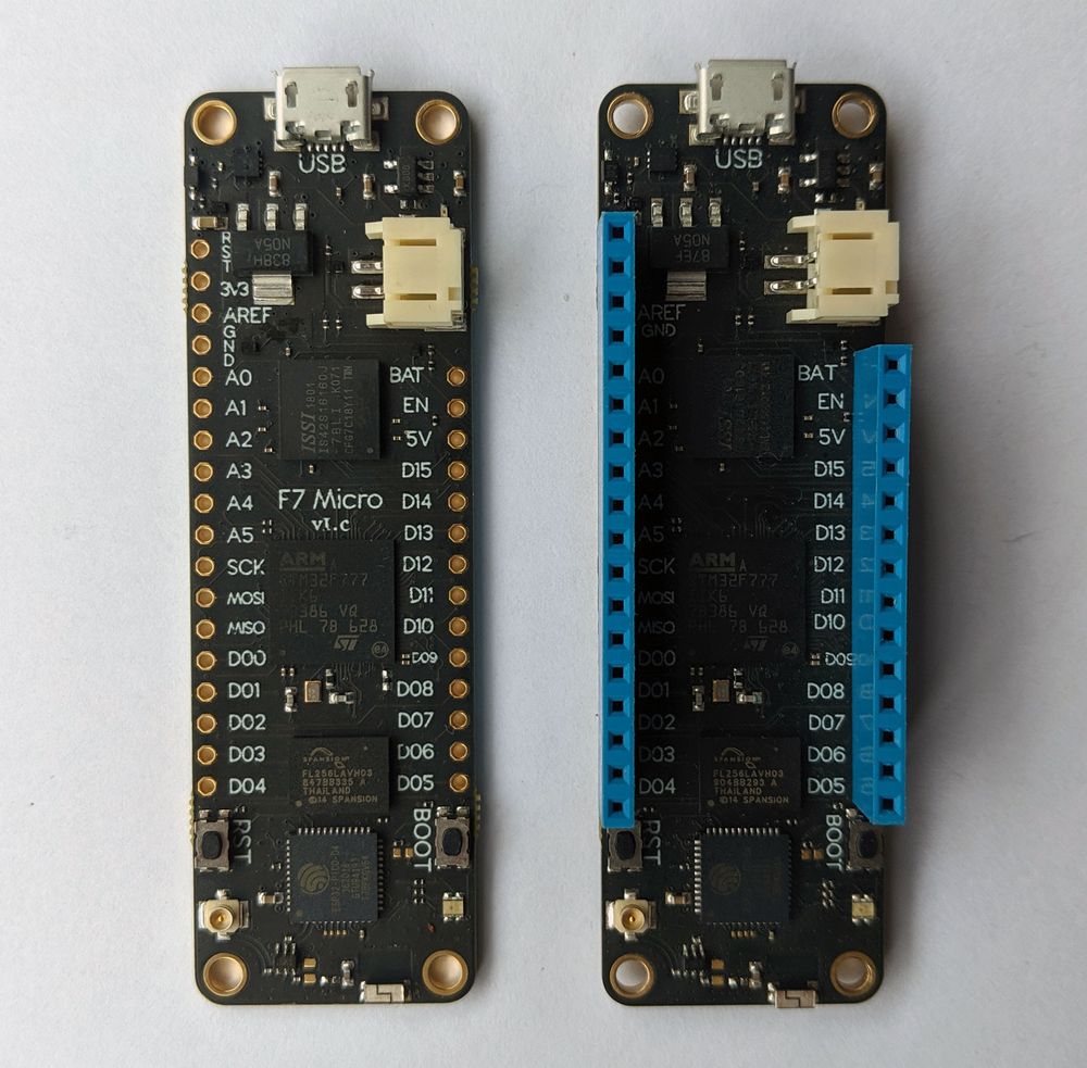 Photo of two Meadow boards, left showing raw header through-holes and one showing blue headers soldering through holes.